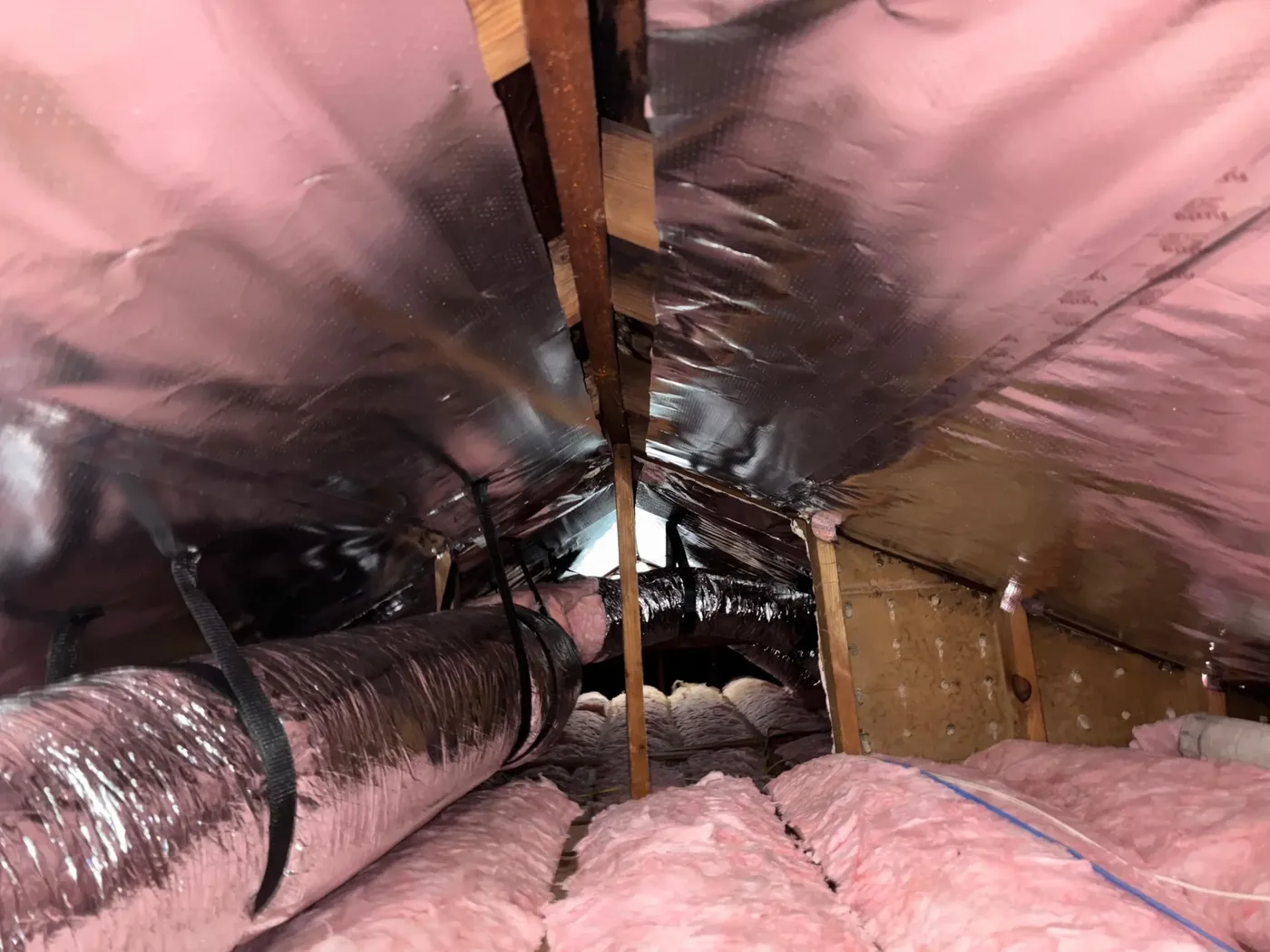 An attic lined with reflective radiant barrier, new ducts and pink fiberglass batts
